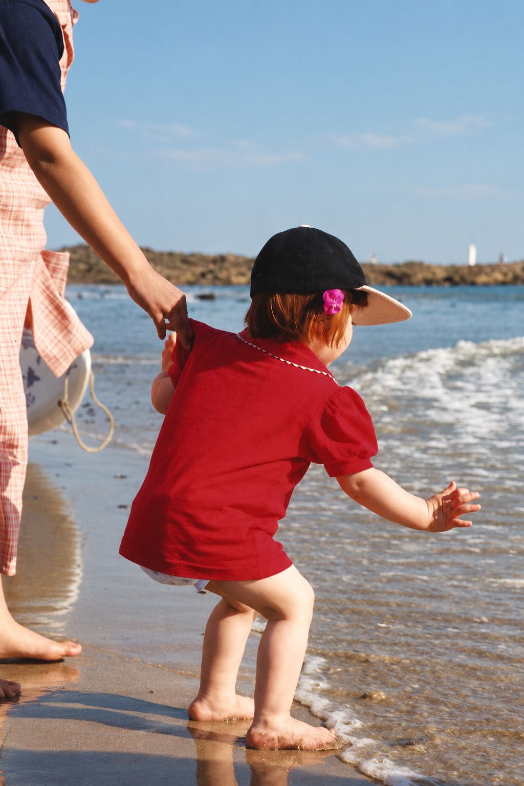 Une enfant tenue par la main au bord de l'eau